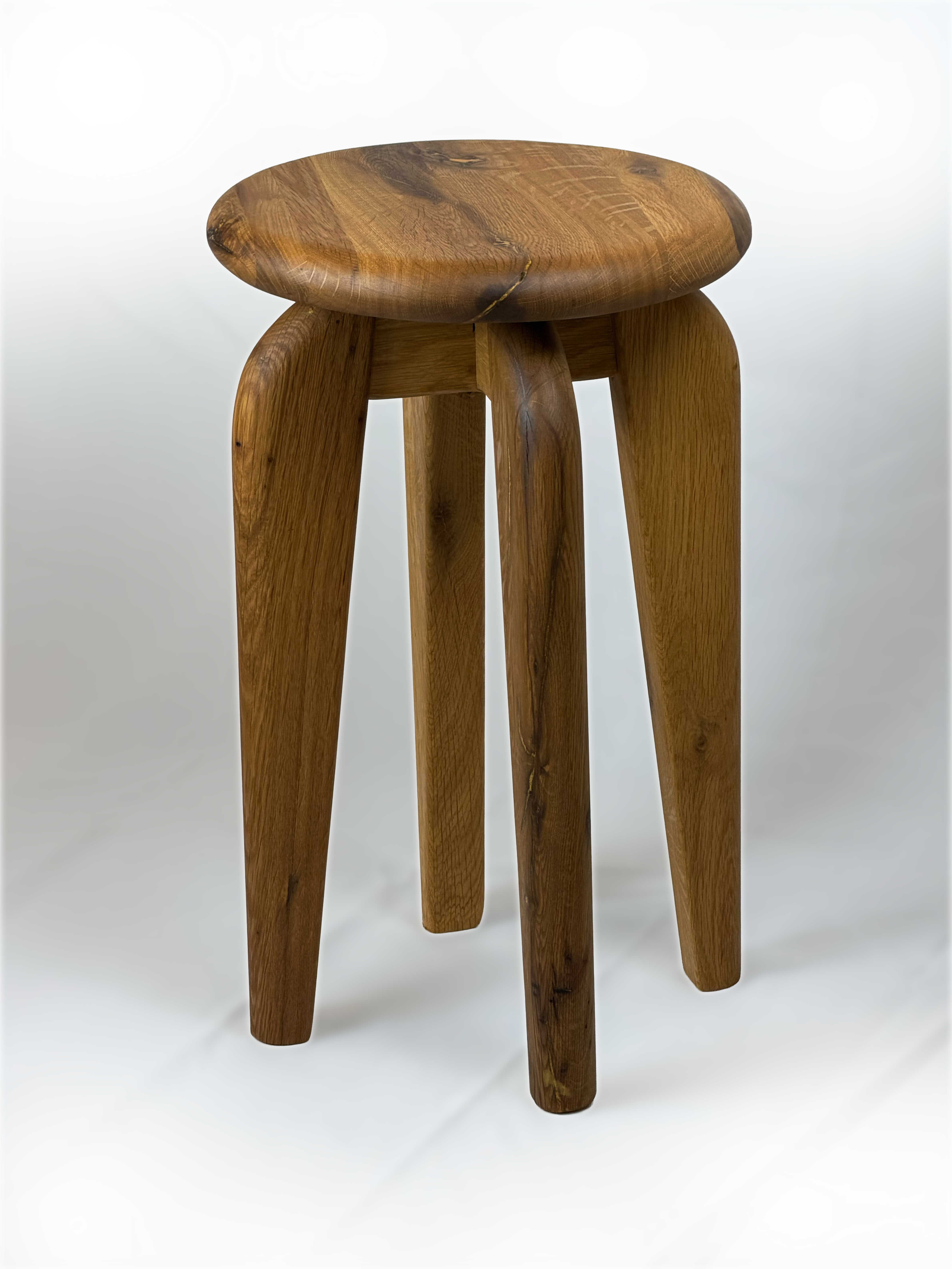 Three-quarters angle view displaying hand-turned splayed legs and organic seat contour